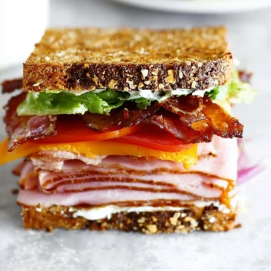 Delectable club sandwich with turkey, ham, and bacon layers stacked high