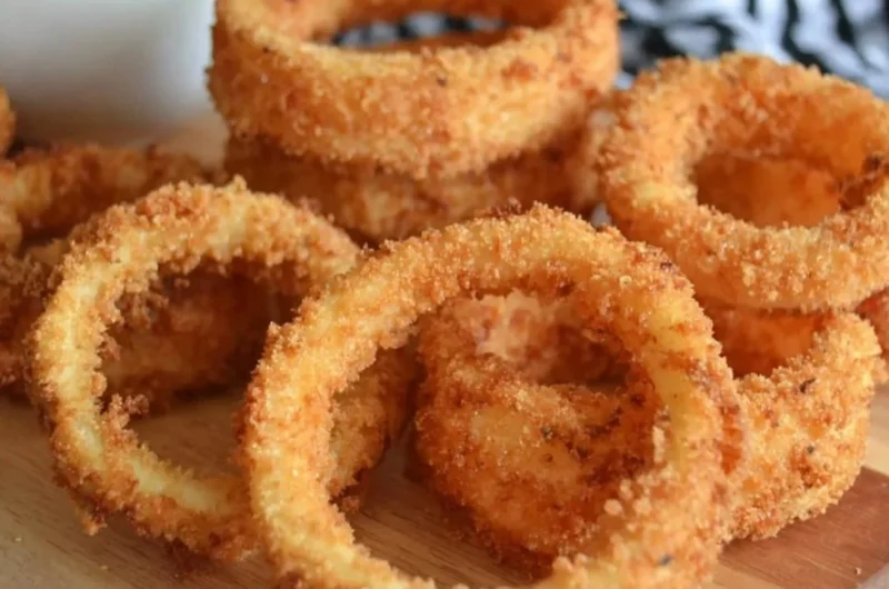 A plate of crispy onion rings with a golden-brown coating
