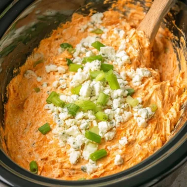 Delicious Crockpot Buffalo Chicken Dip garnished with green onions and served with chips.