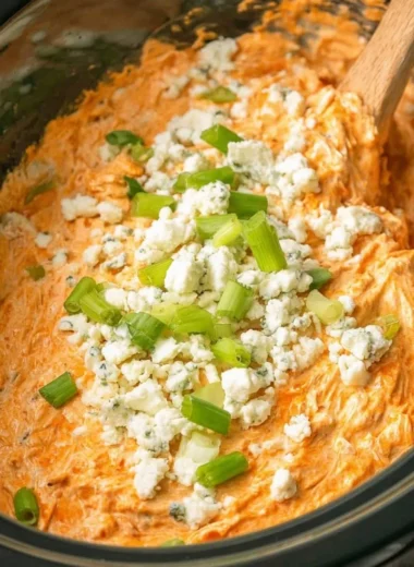 Delicious Crockpot Buffalo Chicken Dip garnished with green onions and served with chips.