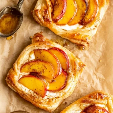 Mini peach and cream cheese tarts served on a white plate, garnished with fresh mint.