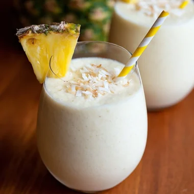3 Ingredient Easy Piña Colada Smoothie served in a glass with a tropical backdrop.