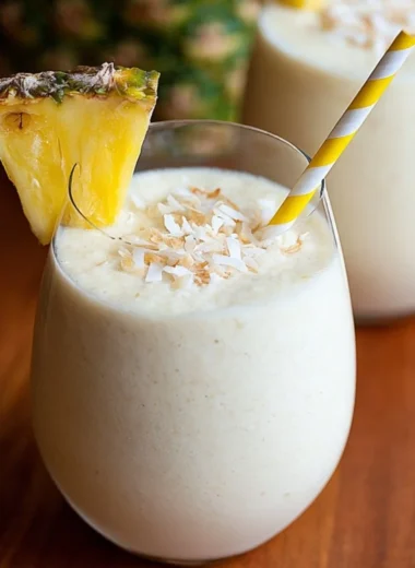 3 Ingredient Easy Piña Colada Smoothie served in a glass with a tropical backdrop.