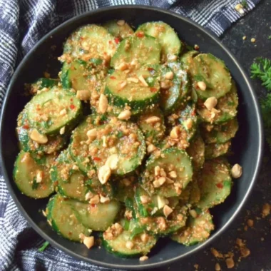 Cucumber salad topped with peanut sauce, garnished with herbs