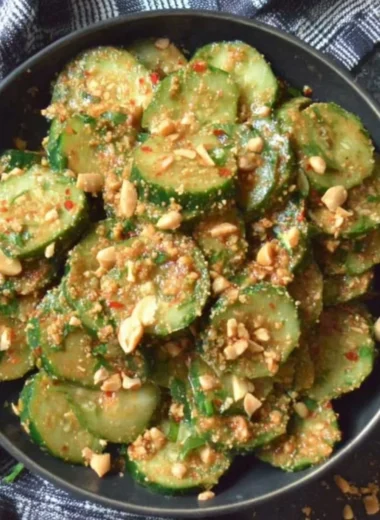 Cucumber salad topped with peanut sauce, garnished with herbs