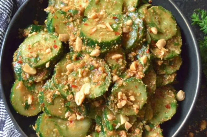 Cucumber salad topped with peanut sauce, garnished with herbs