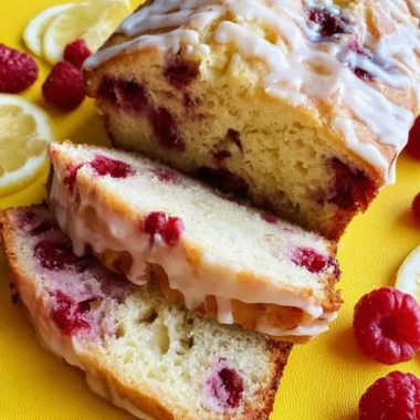 A freshly baked Raspberry Lemon Loaf garnished with raspberries and lemon slices