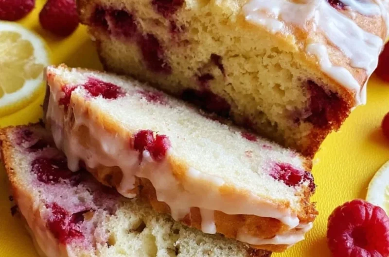 A freshly baked Raspberry Lemon Loaf garnished with raspberries and lemon slices