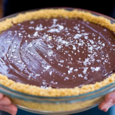 Slice of salted bourbon chocolate pie topped with sea salt and chocolate drizzle