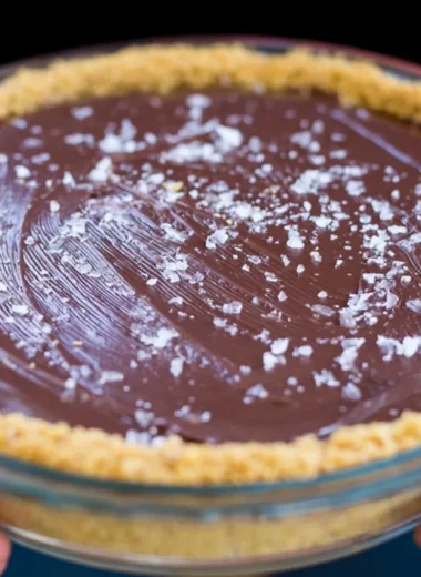 Slice of salted bourbon chocolate pie topped with sea salt and chocolate drizzle