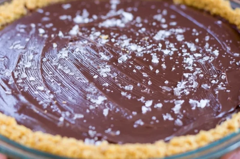Slice of salted bourbon chocolate pie topped with sea salt and chocolate drizzle