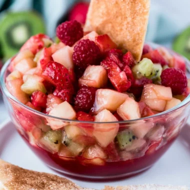Sweet fruit salad served with cinnamon sugar tortilla chips in a colorful bowl.