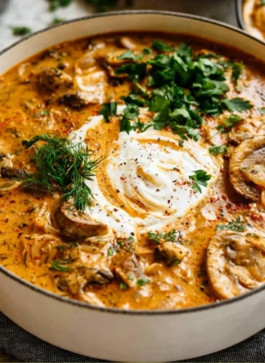 Bowl of creamy Hungarian mushroom soup garnished with herbs and spices