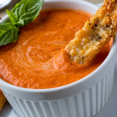 Creamy tomato soup served with Saltine crackers in a bowl