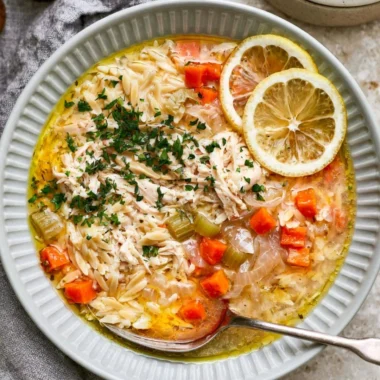 Bowl of Greek lemon chicken soup garnished with herbs and lemon slices