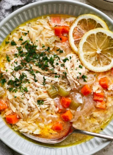 Bowl of Greek lemon chicken soup garnished with herbs and lemon slices