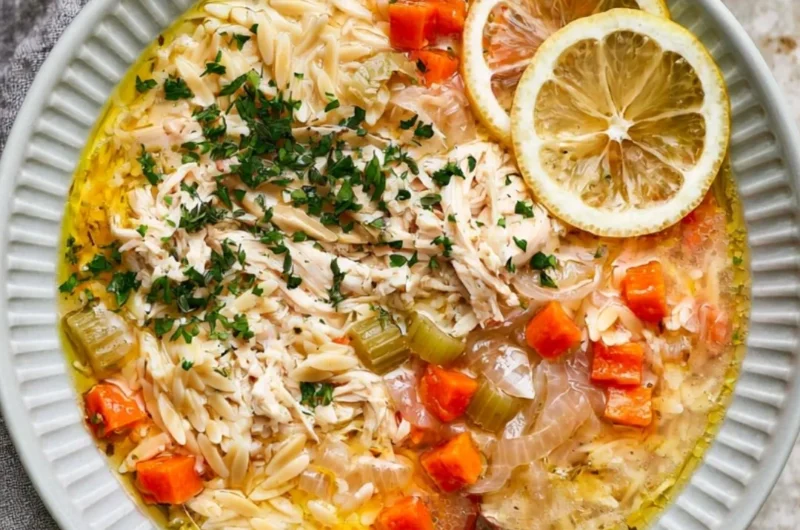 Bowl of Greek lemon chicken soup garnished with herbs and lemon slices