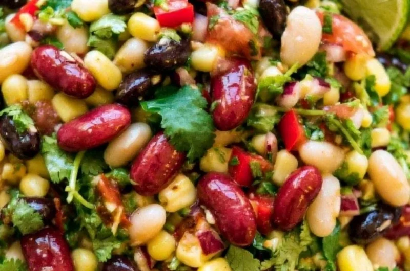 A colorful bowl of healthy Mexican Bean Salad with beans, vegetables, and dressing
