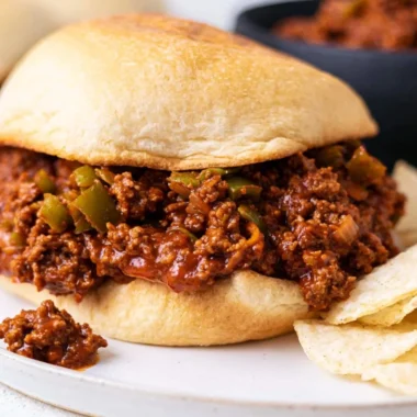 Delicious homemade sloppy joe sandwich served with pickles and fries.