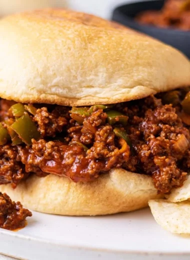 Delicious homemade sloppy joe sandwich served with pickles and fries.