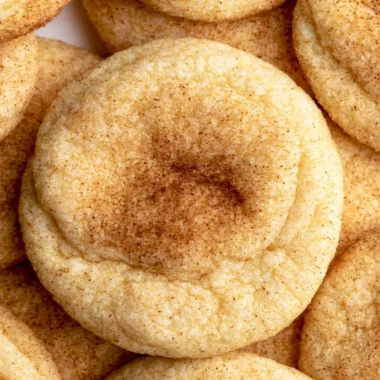 Freshly baked snickerdoodles topped with cinnamon and sugar on a cooling rack.