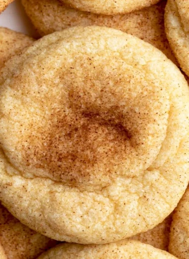 Freshly baked snickerdoodles topped with cinnamon and sugar on a cooling rack.