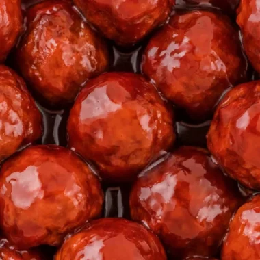 Crockpot meatballs in grape jelly and BBQ sauce served on a platter.